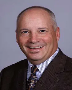 David Hall wearing black suit with brown and black tie.